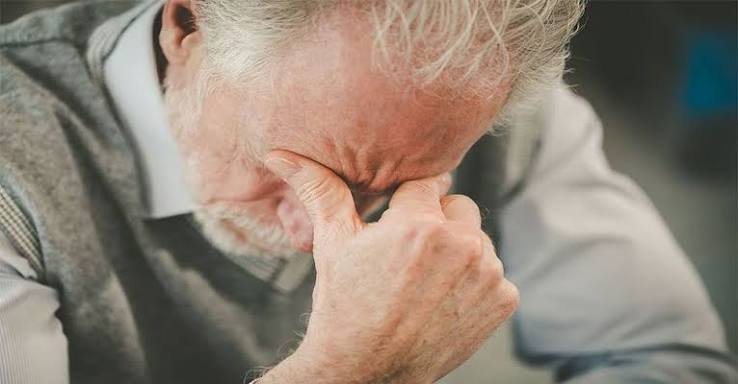 Pessoa idosa com a mão no rosto, em expressão de preocupação